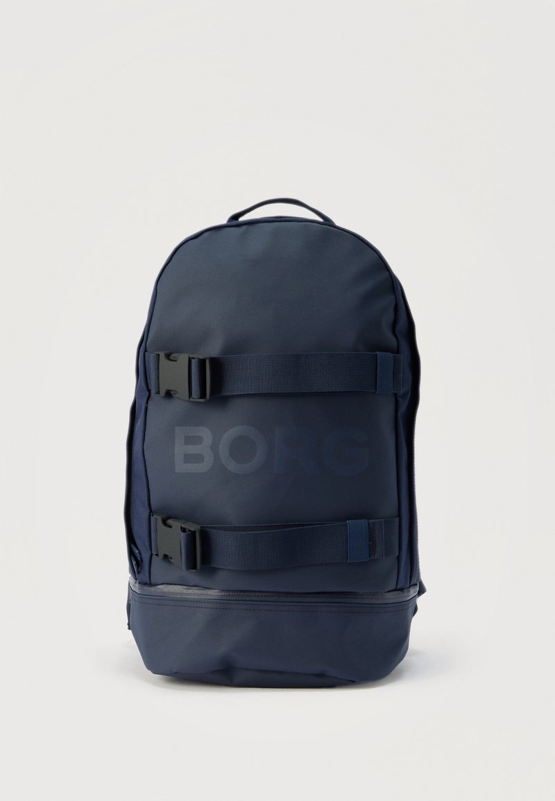 Σακίδιο πλάτης σε ναυτικό μπλε χρώμα με δύο οριζόντιους ρυθμιζόμενους ιμάντες και αγκράφες στο μπροστινό μέρος, καθώς και μια θήκη με φερμουάρ στο κάτω μέρος, όρθιο.