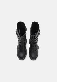 Black leather combat boots featuring multiple buckled straps, rounded toes, and textured soles. Zipper detail on the outer sides.