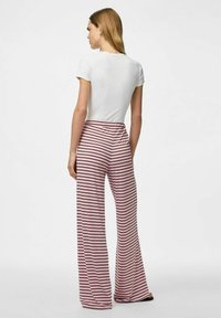 Witte top met korte mouwen gecombineerd met roze en witte gestreepte wijde broek met een elastische tailleband. Gladde textuur en casual pasvorm.