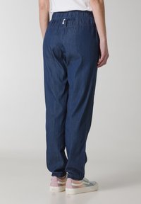 Blaue Denim-Jogginghosen mit elastischem Bund und Bündchen, die eine lockere Passform und minimalistische Nähdetails aufweisen.