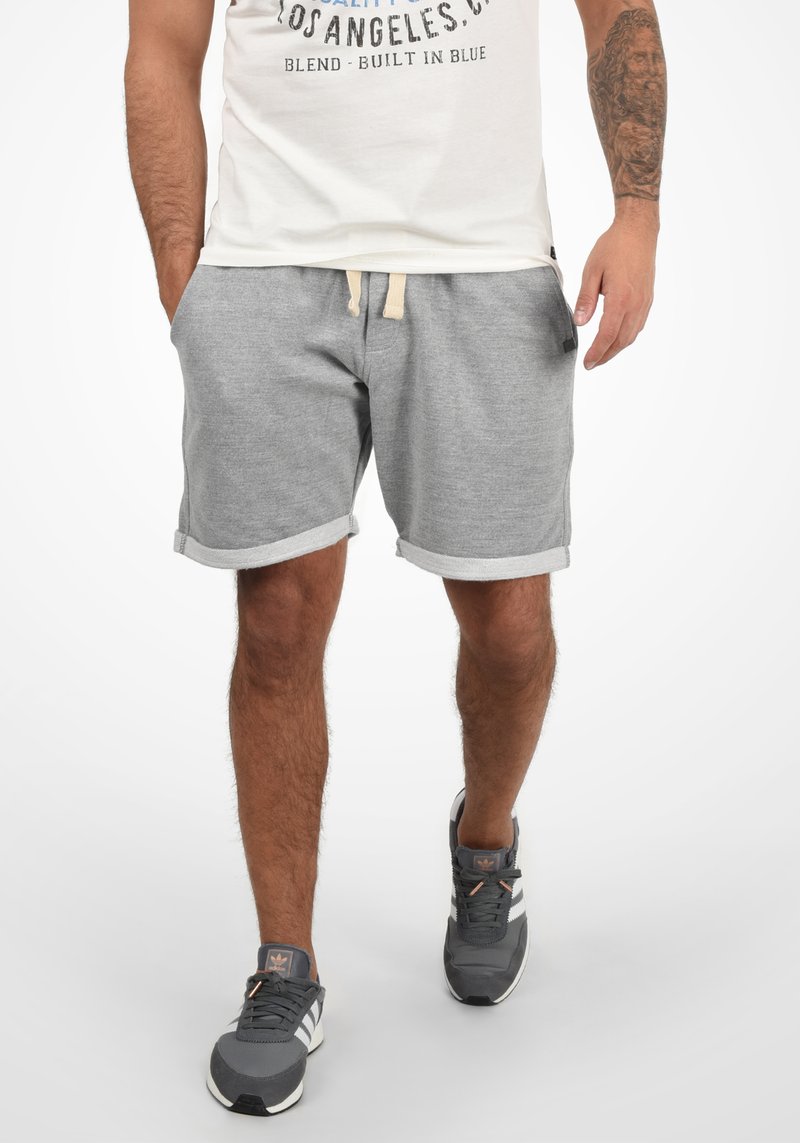 Gray cotton shorts with a drawstring waist, rolled cuffs, and side pockets. Worn with gray athletic shoes and a light-colored T-shirt.