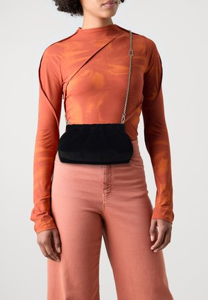 Melns samta maisiņš ar savilkta augšdaļa un sudraba ķēdes siksna, valkāts virs oranžiem garām piedurknēm topa un gaiši rozā augstiem biksēm.