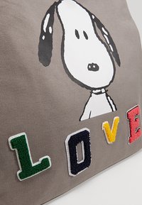 Tête de chien dessin animé en noir et blanc au-dessus de lettres texturées colorées formant le mot « AMOUR » sur fond de tissu gris.