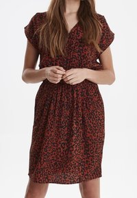 Leopardmönstrad klänning i rost och svart, korta ärmar, knappfront, elastisk midja, knälång, lätt tyg med en mjuk textur.