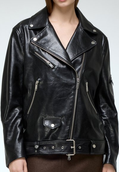 Black leather biker jacket with silver zippers, snap buttons, and a belted waist. Features a wide collar and multiple zippered pockets.