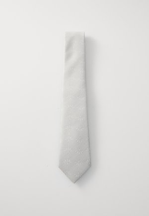 Cravate gris clair avec un motif subtil, présentant une texture lisse et une pointe aiguisée, disposée à plat sur un fond blanc.