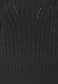 Schwarzer gerippter Pullover mit vertikalen Streifen und kleinen Rauten-Ausschnitten am Halsauschnitt. Hergestellt aus weichem, strukturiertem Stoff.