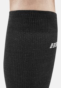 Schwarze gerippte Kniehochsocken mit strukturiertem Oberflächen und weißen Logodetails. Hergestellt aus dehnbarem Material für Komfort und Passform.
