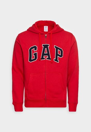 Roter Zip-Hoodie mit Fronttaschen, Kordelzugkapuze und großen schwarzen und weißen "GAP"-Buchstaben auf der Brust.
