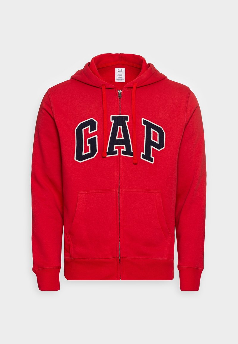 Sweat à capuche rouge zippé avec poches avant, capuche à cordon et grandes lettres "GAP" noires et blanches sur la poitrine.