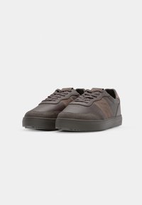 Sneakers bruns foncés avec un mélange de panneaux lisses et texturés, bout rond, design à lacets et semelle extérieure épaisse en caoutchouc.