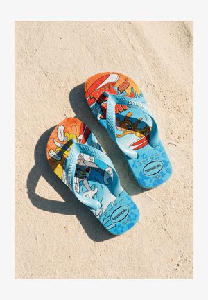 Tongs bleues pour enfants sur le sable avec les personnages de dessin animé Tom et Jerry, avec des brides bleu clair et la marque "havaianas".