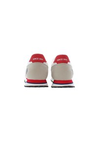 Pair of beige and white sneakers with red accents, "Since 1890" text on heels, viewed from the back on a white background.