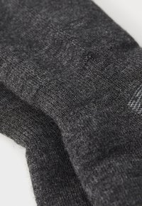 Temno sivi nogavici iz mehkega, teksturiranega materiala, z ribastim vzorcem in subtilnimi motivi, lahki in elastični.