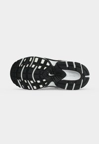 Μαύρη και λευκή σόλα παπουτσιού Nike με υφασμένα σχέδια πρόσφυσης και κεντρικό λογότυπο Nike Swoosh σε απλό ανοιχτό φόντο.