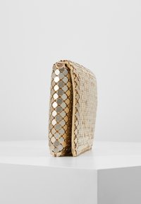 Clutch de color dorado con adornos de lentejuelas hexagonales. Diseño plano, textura suave y un cierre con cremallera en la parte superior.