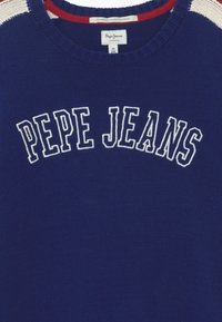 Niebieski sweter z dzianiny z białym napisem "PEPE JEANS", okrągły dekolt, czerwone i białe paski na ramionach, miękka tekstura.