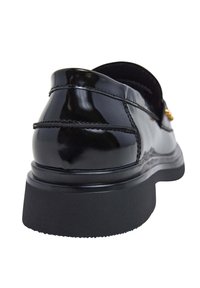 Zwarte nagelrechte leren schoenen met een afgeronde achterkant, voorzien van een verhoogde zool, stikdetails en gouden accenten aan de zijkant.