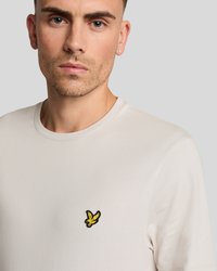 Short-sleeve cream t-shirt made of soft fabric featuring a small yellow and black embroidered banana design on the left chest.