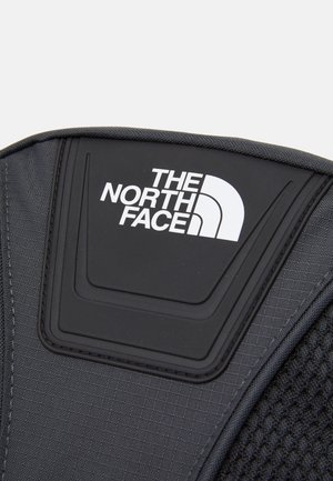 Mustan kangaskuoren olkatuki, jossa on teksturoitu pinta. Sisältää kohotetun, kumitetun "THE NORTH FACE" -logon valkoisena.