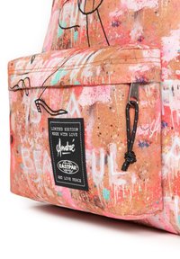 Canvasryggsäck med en livfull rosa och orange abstrakt design. Har ett framfickor med dragkedja, svarta detaljer och en tyglogopatch.