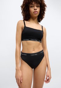 Σετ αποτελούμενο από μαύρο σουτιέν bralette και μαυρα ψηλόμεσα εσώρουχα από απαλό ύφασμα, με λωρίδα μέσης που φέρει το λογότυπο Calvin Klein. Απλό ς και κομψός σχεδιασμός.