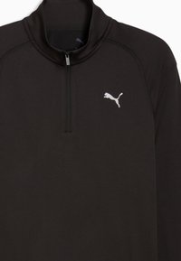 Μαύρο αθλητικό τοπ με μακριά μανίκια, φερμουάρ μέχρι το στήθος και μικρό λευκό λογότυπο Puma στην αριστερή πλευρά του στήθους.