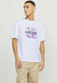 Hvid bomulds T-shirt med et lilla grafisk kvadratdesign og sort tekst "Jack&Jones EST. 1990." Afslappet pasform med korte ærmer.