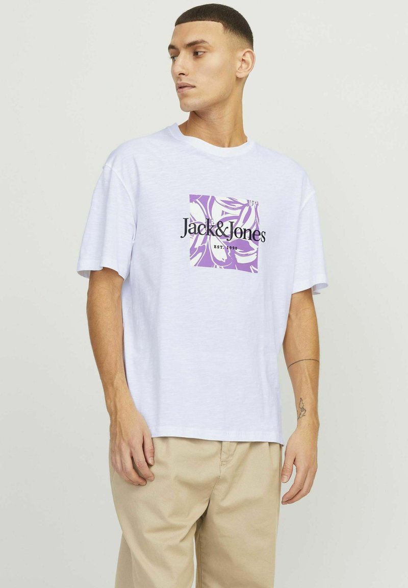 White cotton T-shirt featuring a purple graphic square design and black text "Jack&Jones EST. 1990." Relaxed fit with short sleeves.