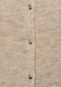 Beiger Strickcardigan mit weicher Textur und fünf metallischen Knöpfen entlang der Vorderseite. Dezente Farbnuancen verleihen dem Material Tiefe.