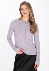 Cardigan lung cu mâneci lungi de culoare mov deschis, cu guler rotund și închidere cu nasturi. Textură moale, design ajustat și manșete striate. Asortat cu o fustă neagră.