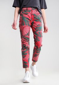 Rode en groene katoenen broek met een bladmotief, met een slim fit en zijzakken, gecombineerd met witte sneakers.