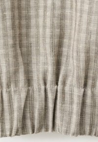 Béžová ľanová látka s vertikálnymi pásikmi a nariaseným elastickým švom vytvára jemné záhyby a textúru.