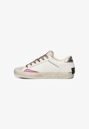 Zapatilla blanca con detalles metálicos, puntera texturizada en color beige, cordones de estampado animal y un detalle de diseño rosa en el lateral. Suela de goma.