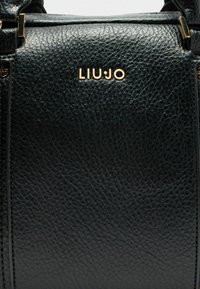 Crna torba od teksturirane kože s zlatnim "LIU JO" logotipom, strukturiranim dizajnom i diskretnim metalnim detaljima.