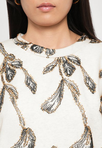 White sweatshirt featuring black floral embroidery with golden accents around the collar and pattern, smooth texture, and relaxed fit.