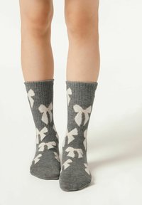 Graue Stricksocken mit weißen Schleifenmustern, ausgestattet mit gerippter Struktur und umgeschlagenem Bündchen, geeignet für die Freizeit.
