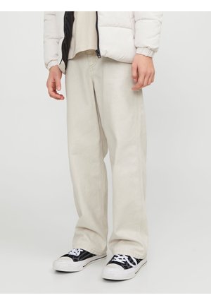 Beige vidde bukser med lige pasform, lavet af blødt stof, med synlige sømme. Parret med sort-hvide sneakers.