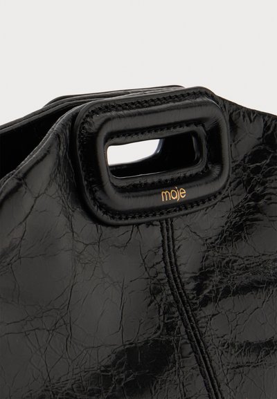 Sac en cuir noir texturé avec poignée découpée rectangulaire, bords cousus et petit logo doré "maje" sous la poignée.