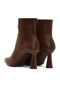 Bottines en cuir marron avec un bout pointu, texture lisse et talons courts et évasés distincts. Présentent une fermeture éclair latérale.