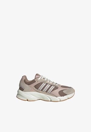 Baskets athlétiques beige et marron avec des lacets blancs, des panneaux en mesh et en daim, une semelle blanche et des bandes signature sur le côté.