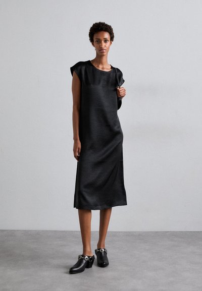 Black satin dress with short sleeves, smooth texture, knee-length, paired with black clogs featuring decorative silver hardware accents.