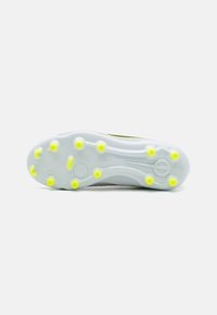Crampons de football avec un dessus gris, texture lisse, et une semelle blanche translucide dotée de taquets jaunes pour la traction.