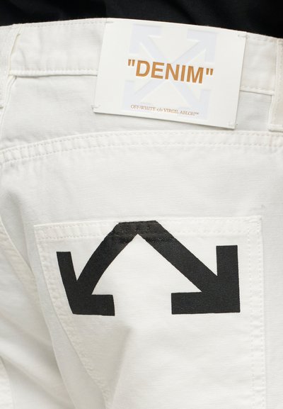 Λευκό τζιν παντελόνι με μαύρο λογότυπο διπλού βέλους στην πίσω τσέπη και λευκή ετικέτα με την επιγραφή «DENIM» από Off-White c/o Virgil Abloh.