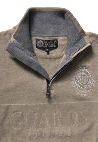 Beżowy polar zapinany na zamek z szarym kołnierzem, wykonany z fakturowanej tkaniny. Logo wyszyte na piersi, z wyraźnym napisem "GUARDS POLO CLUB".