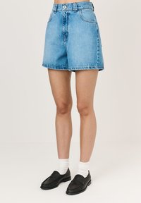 Heledad sinised teksapüksid kõrge taljega ja laia lõikega. Tooriku servade detail, küljetaskud ja klassikaline viie tasku disain.