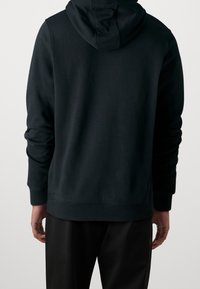 Zwarte hoodie gemaakt van zachte stof, voorzien van een capuchon met trekkoord en geribbelde manchetten. Eenvoudig, onopgesmukt ontwerp met een relaxte pasvorm.