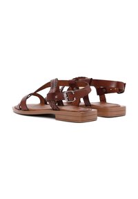 Sandalias de cuero marrón con tiras trenzadas, cierre de hebilla y suela rectangular plana. Textura suave con un diseño minimalista.