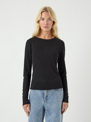 Sort langermet ribbestrikket topp med rund hals og tettsittende design, sammen med lyseblå høytlivs jeans.