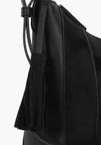 Borsa nera con una combinazione di pelle liscia e suede testurizzato, dotata di un dettaglio decorativo a nappe. La forma elegante e curva esalta il design.